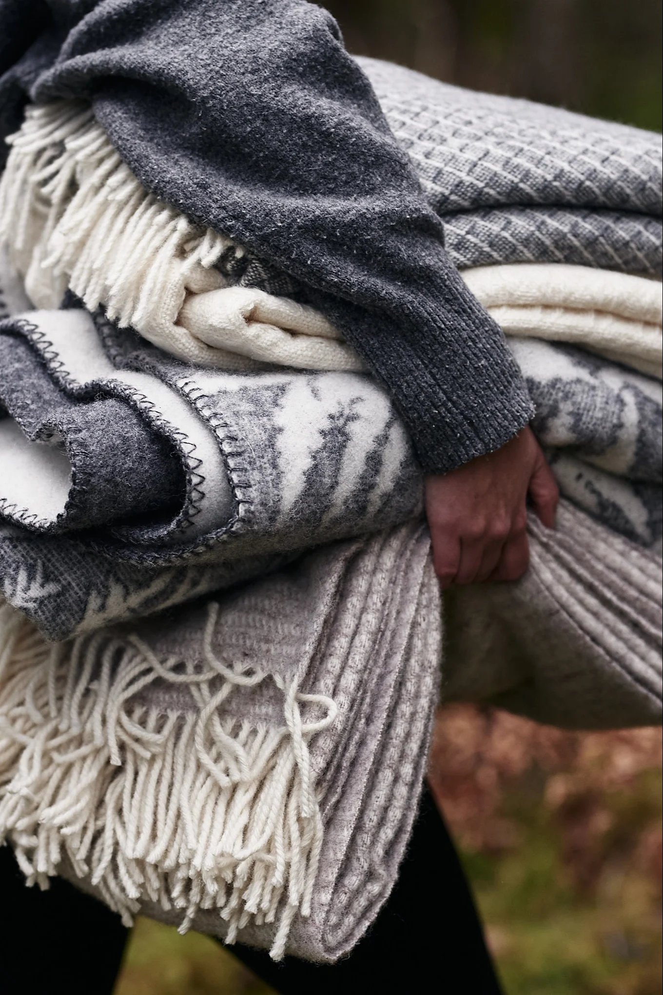 En hög med ullplädar bärs under armen på väg till glöggminglet i skogen. 