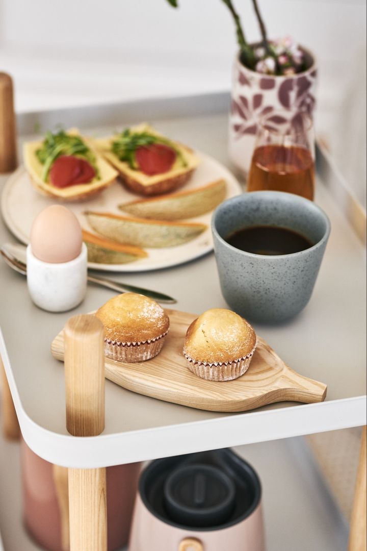 Söta muffins serverade på en träbricka ihop med nybryggt kaffe blir en lyxig frukost och god start på helgen. 