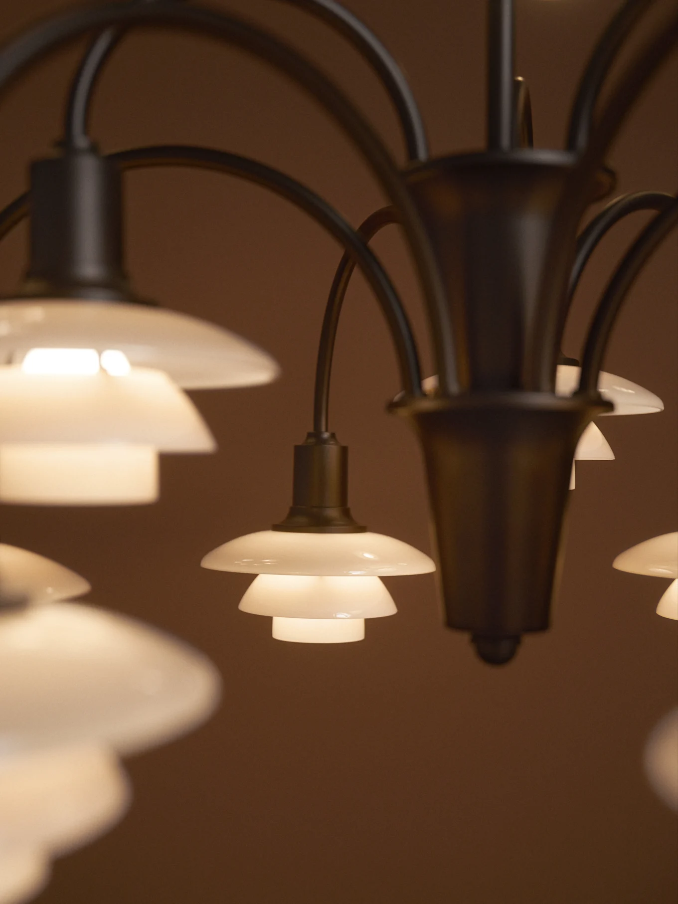 Lampa med flera glödande, flerskiktade frostade glasskärmar mot en mörk bakgrund.