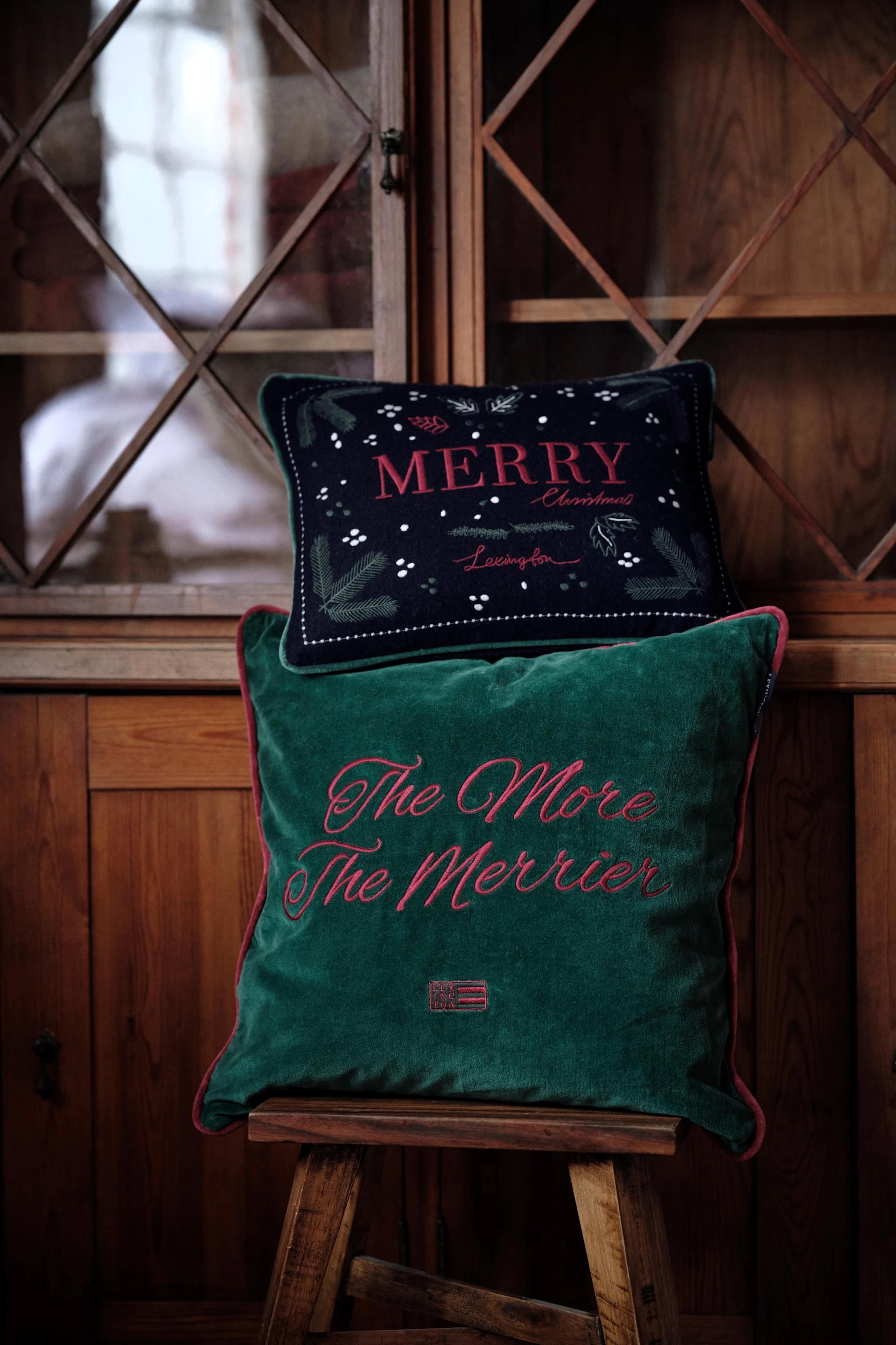 Kuddar är en populär juldekoration 2025: Här ligger två juliga kuddar från Lexington på en pall.