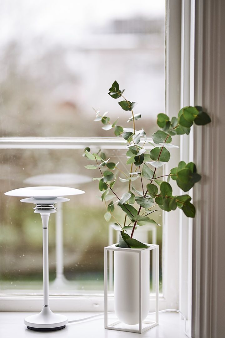 Inredning i skandinavisk stil till matplatsen innebär bland annat en vit bordslampa i fönstret tillsammans med vas med blommor. 