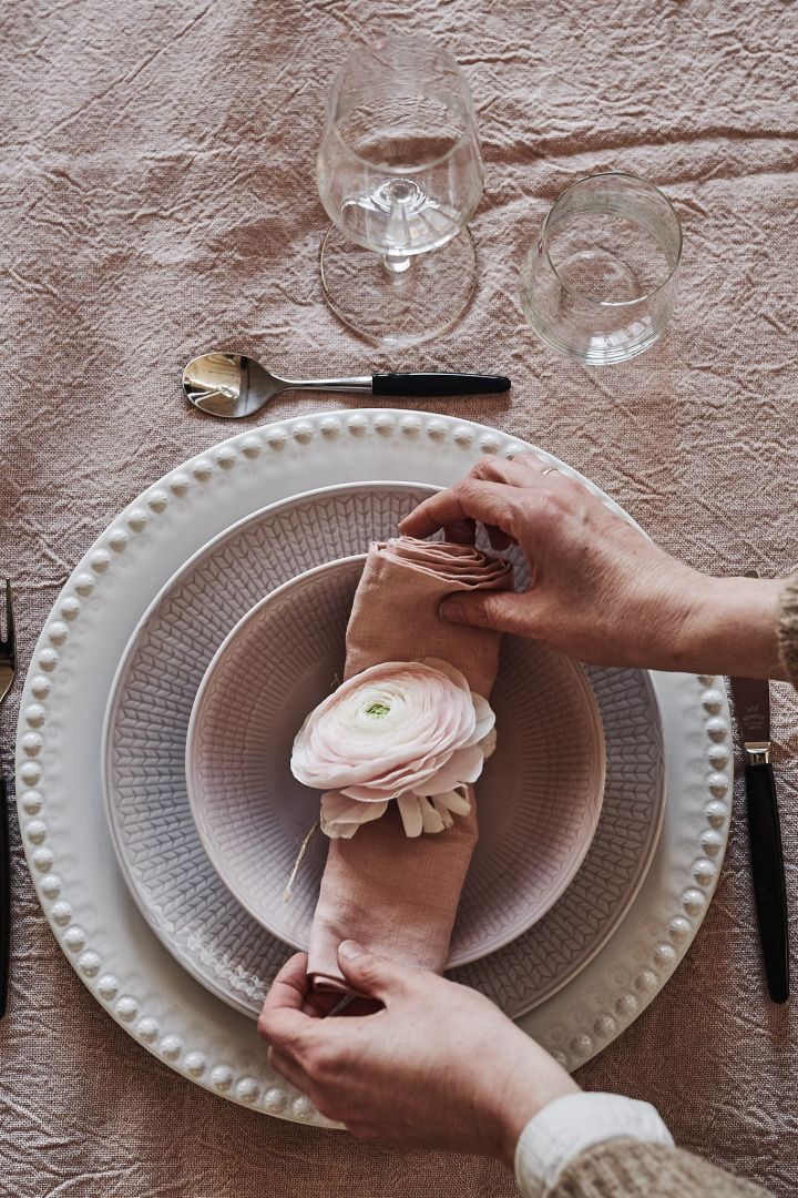Ett tips på att vika servetter är att rulla linneservetten som här i bild, och lägga på tallriken med en blomma på som dekoration. 