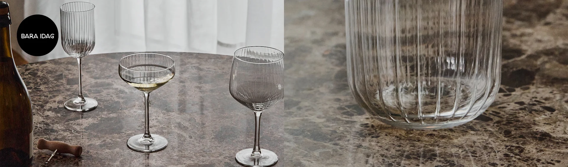 En flaska, korkskruv och tre olika räfflade glas på ett marmorbord, varav ett med vitt vin.
