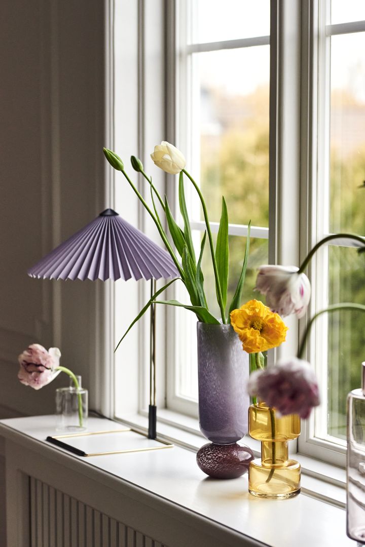 Inreda fönsterbräda – inspiration där lila Matin bordslampa från HAY och vaser från Broste Copenhagen, Bloomingville och DBKD skapar en ombonad känsla.