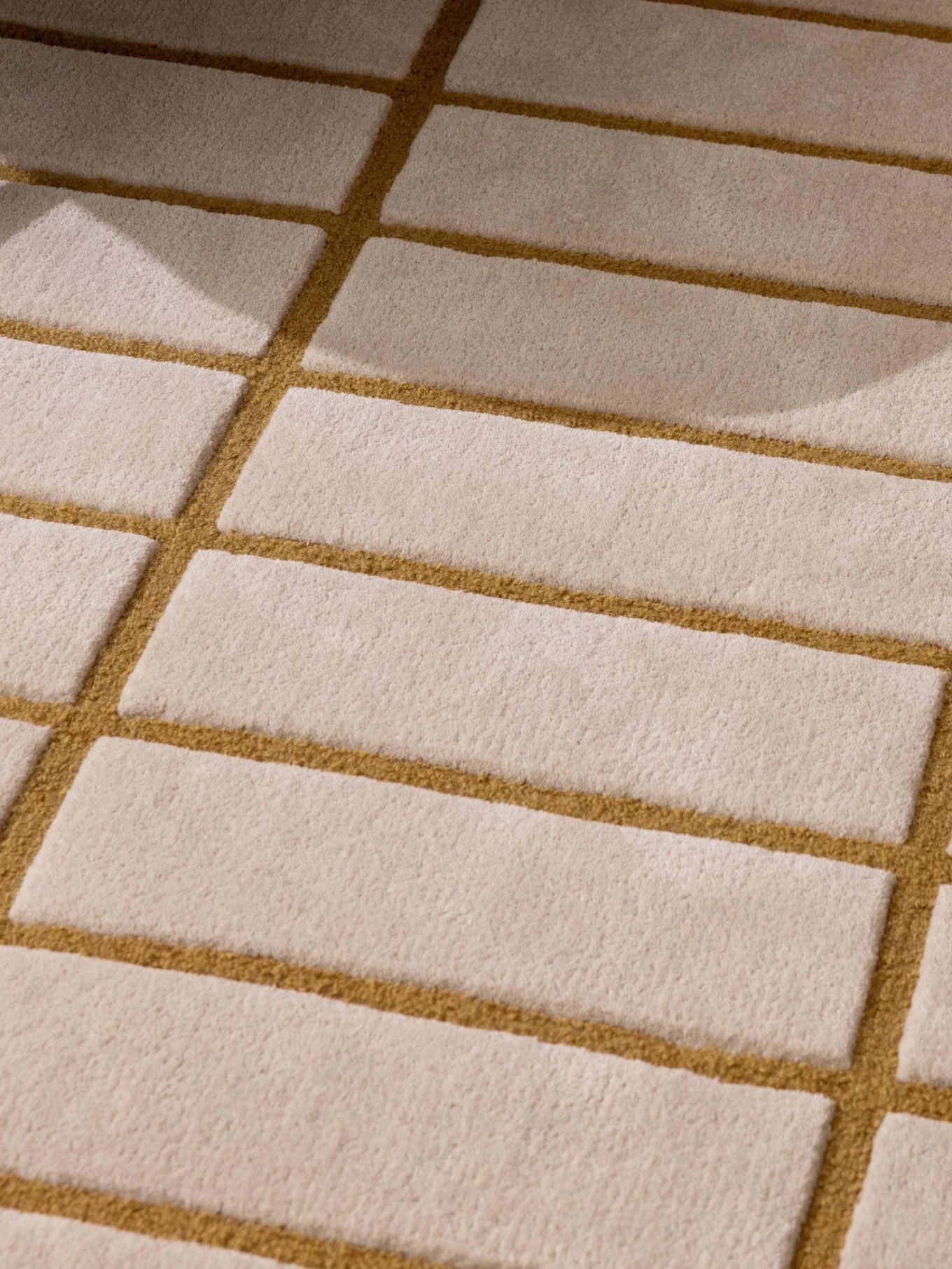 Mönstrad beige och gyllenbrun matta, grönt fåtöljben och en bricka med vit tekanna och kopp.