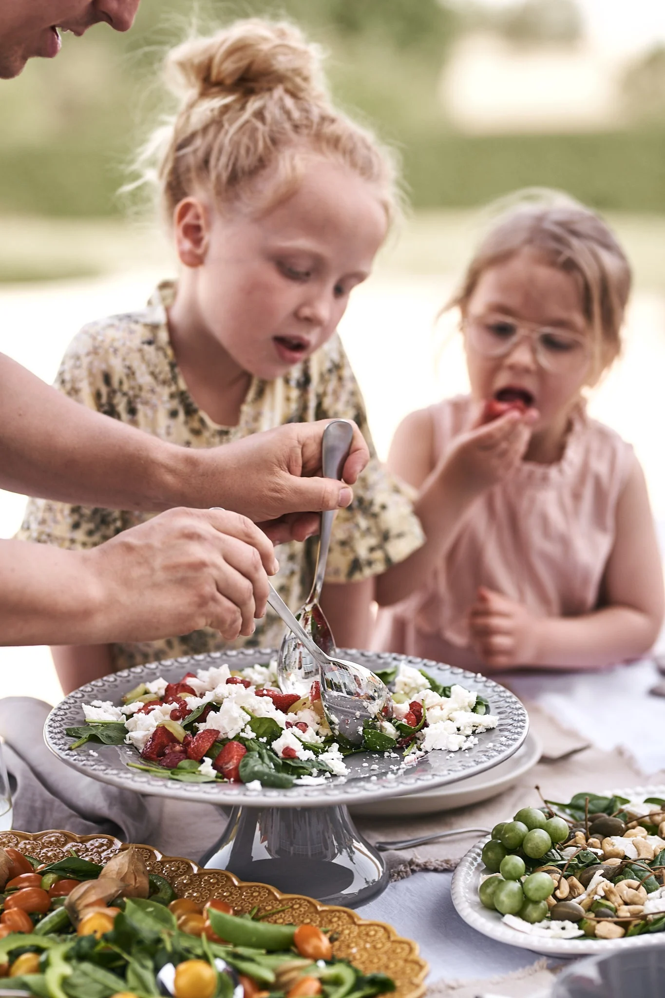 Det bjuds på fräsch sommarsallad gjord på jordgubbar och fetaost på sommarlunchen vilket uppskattas av barnen runt bordet.