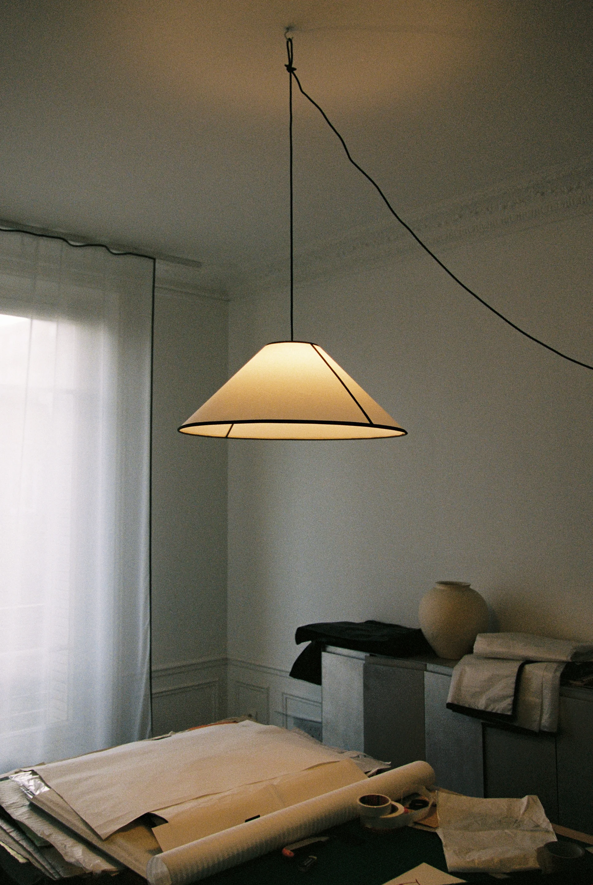 Ett mysigt rum med en gräddfärgad fluffig fåtölj, en beige justerbar golvlampa och en mörk trähylla med konst och böcker.