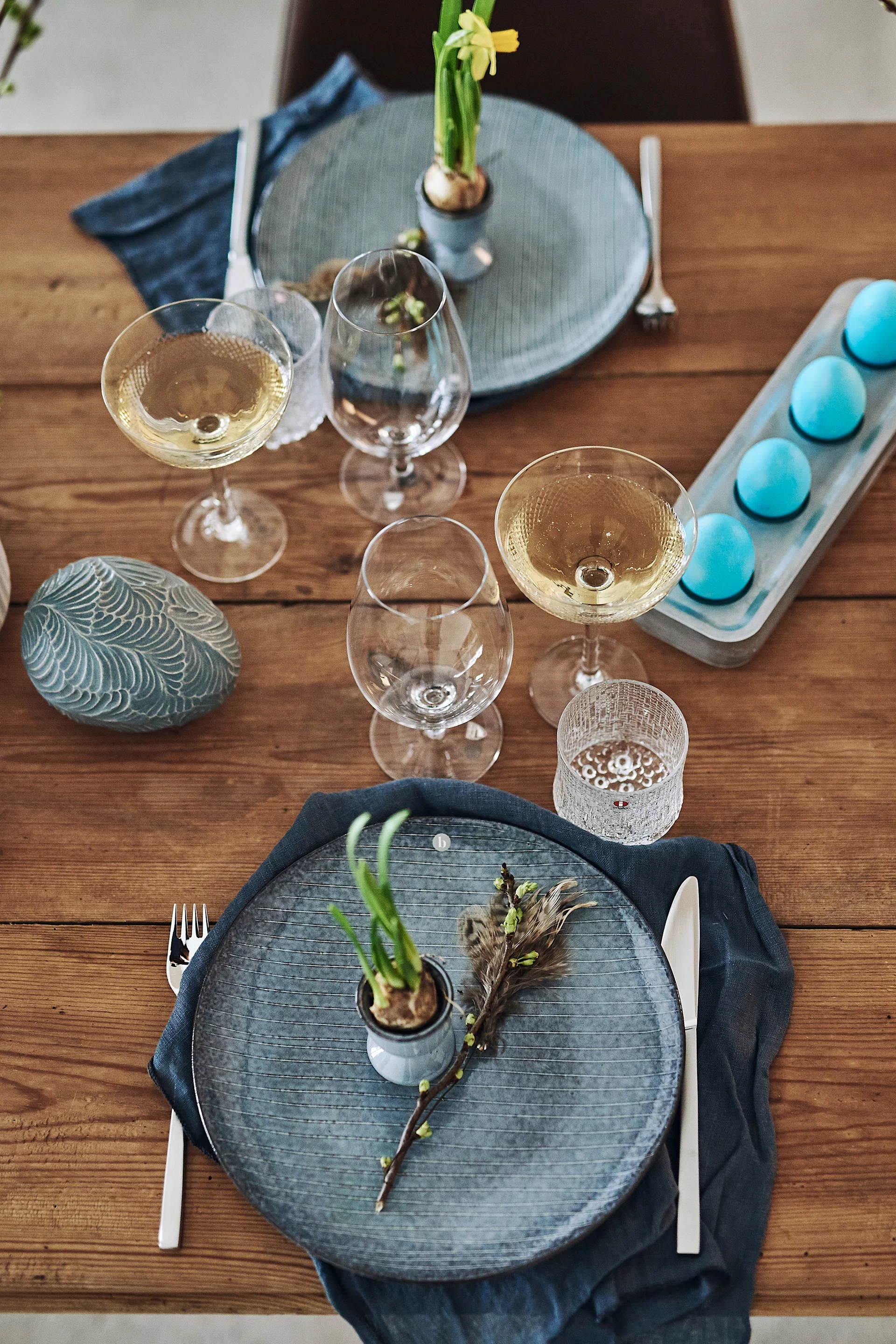 En fin påskdukning i rustik stil med tallrikar i stengods och påsklilja i äggkopp på tallriken.