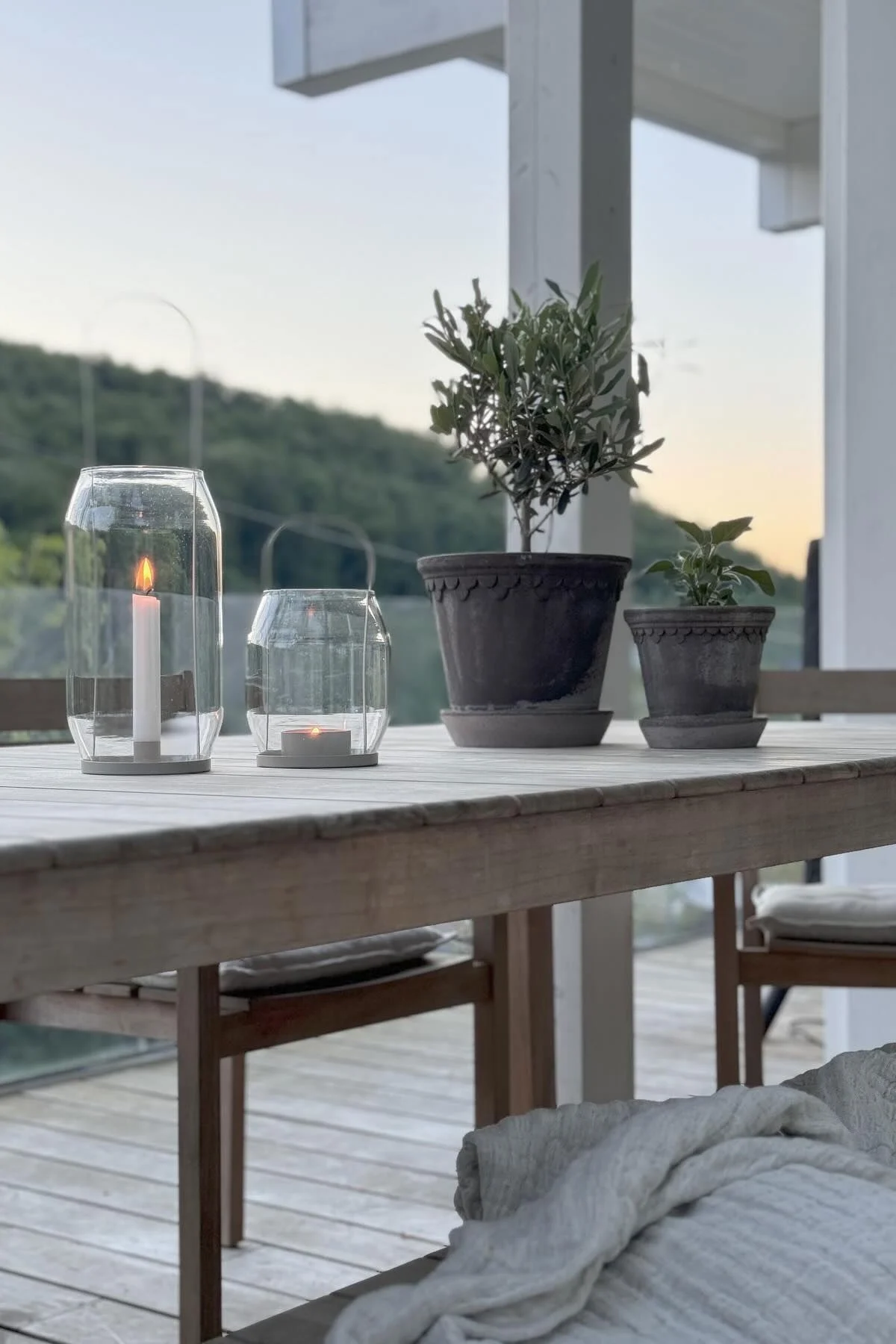 Två grå blomkrukor från Copenhagen står på ett bord bredvid två Ernst-lyktor i olika storlekar på @zuhauseligs terrass.