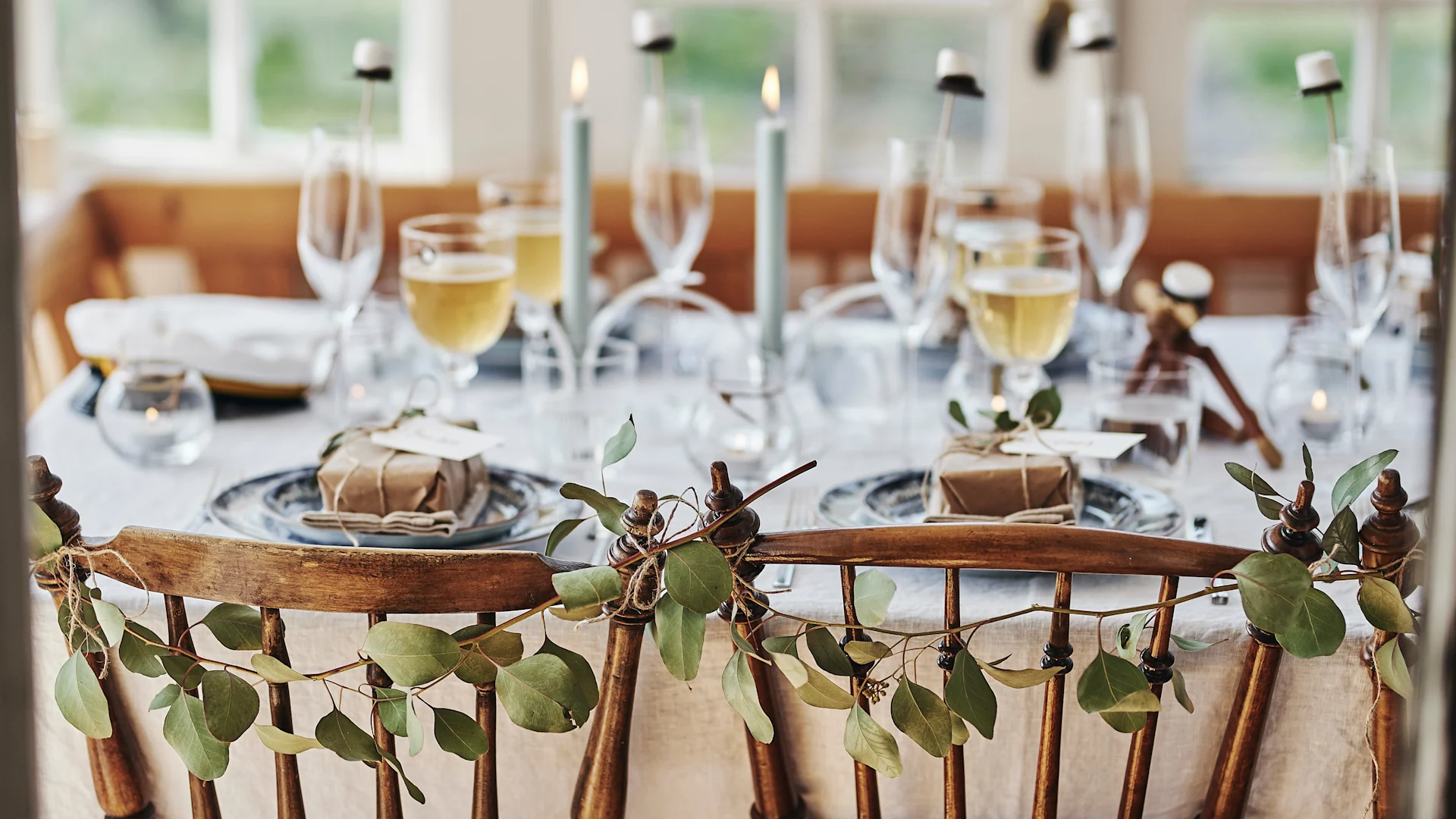 Studentfest-dekoration – halvkransar av eukalyptus på stolsryggen.