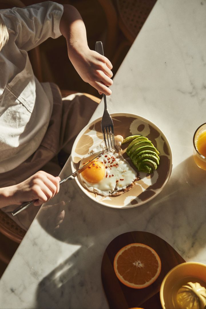 Servera det stekta ägget på Unikko tallrik i vit och beige från Marimekko vid din lyxiga helgfrukost. Tallriken har en vit botten med det karaktäristiska blomstermönstret i beige.
