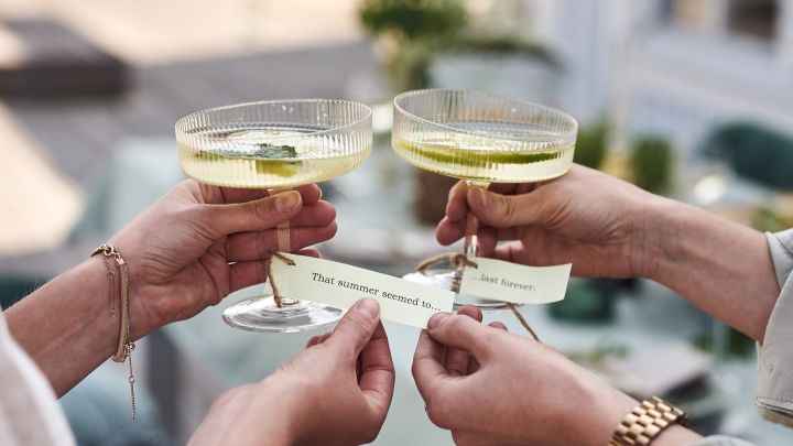Lappar med kända sommarlåtar har knutits runt champagneglasen RIpple som bordsplacering på trädgårdsfesten.