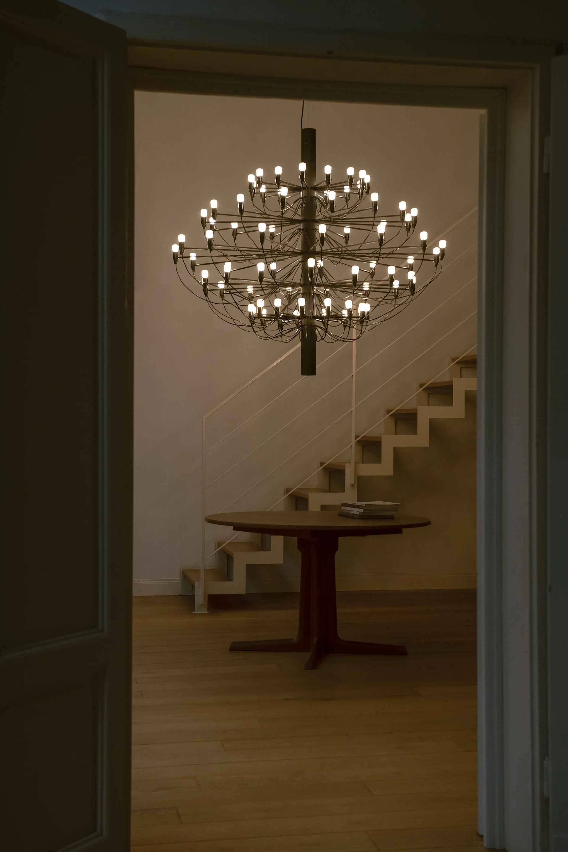 En Sarfatti taklampa i svart som hänger framför en trappa. Lampan tillhör en klassisk designlampa.