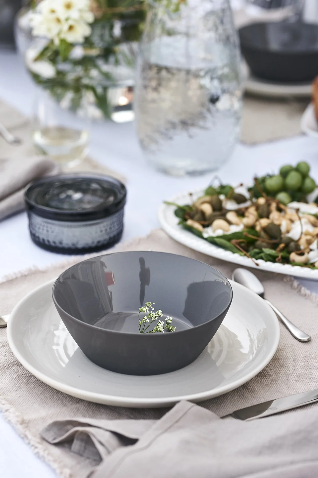 En sommardukning i svala toner för sommarlunch i skuggan med tallrik från ERNST och skål i stengods från Broste Copenhagen.