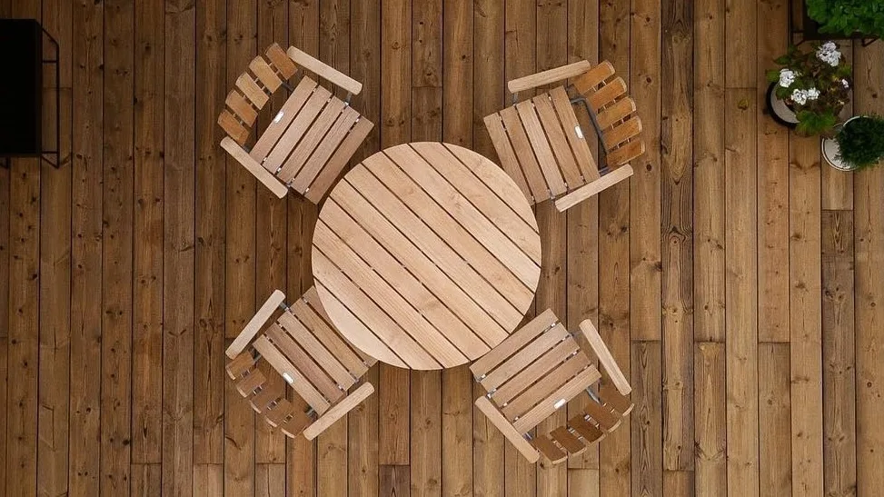 Utemöbler från Grythyttan Stålmöbler i teak på uteplats med trätrall.