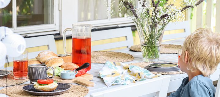 Bild som visar en liten pojke sittandes vid uppdukat frukostbord med nybakade kalljästa frallor.