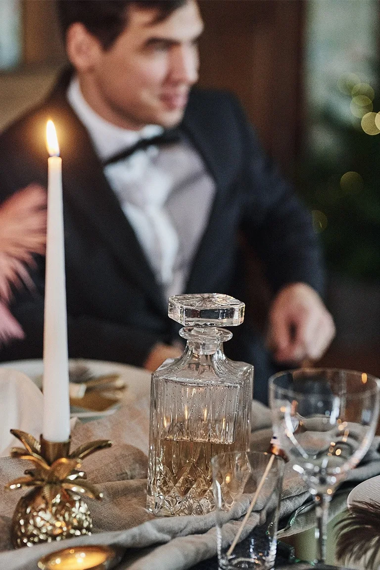 Harvey whiskeykaraff i slipat glas från Aida pryder denna nyårsdukning i guld.