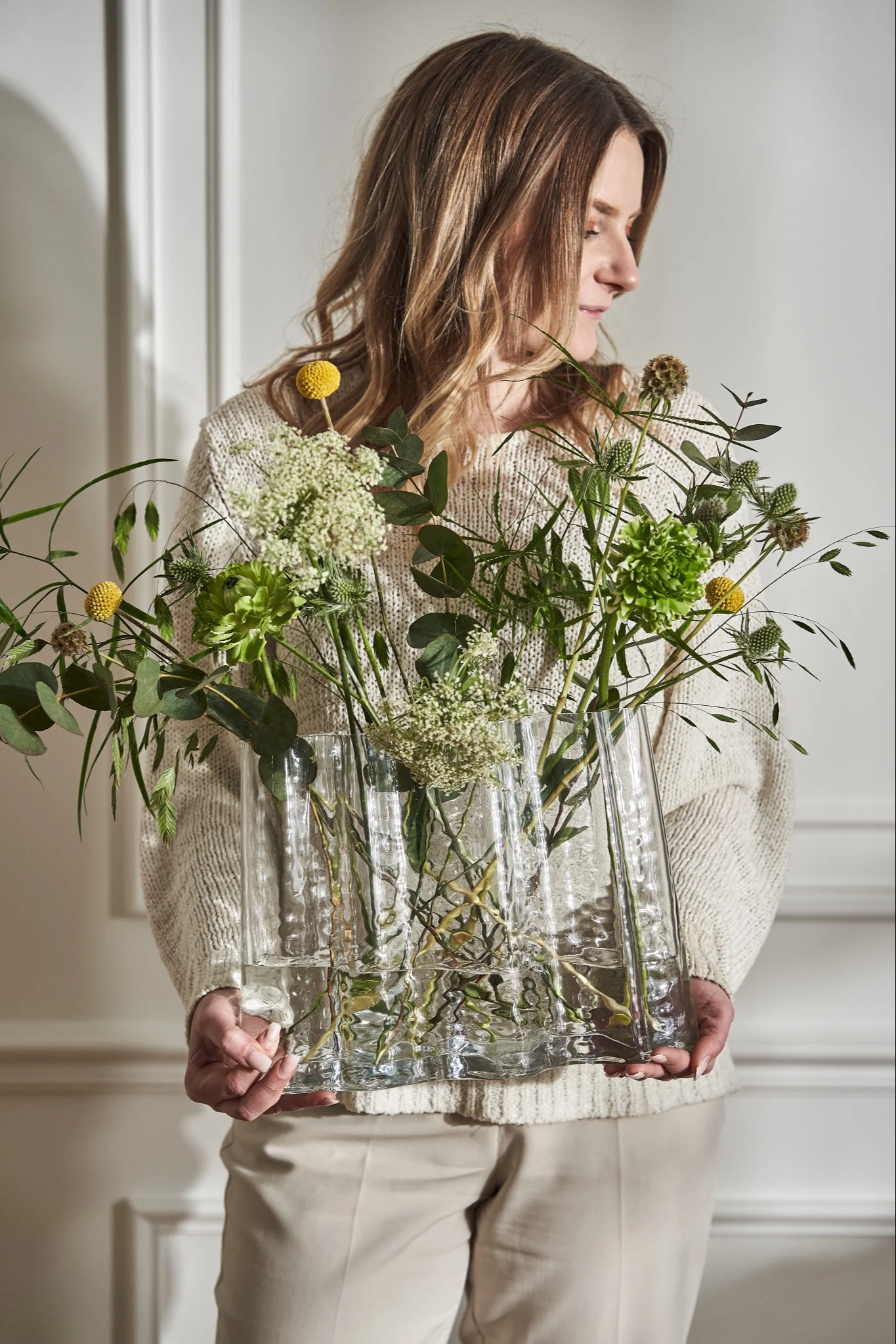 Att välja den bästa vasen för dina snittblommor är inte alltid lätt. Här ser du vasen Gry från Cooee Design som hålls av en kvinna.