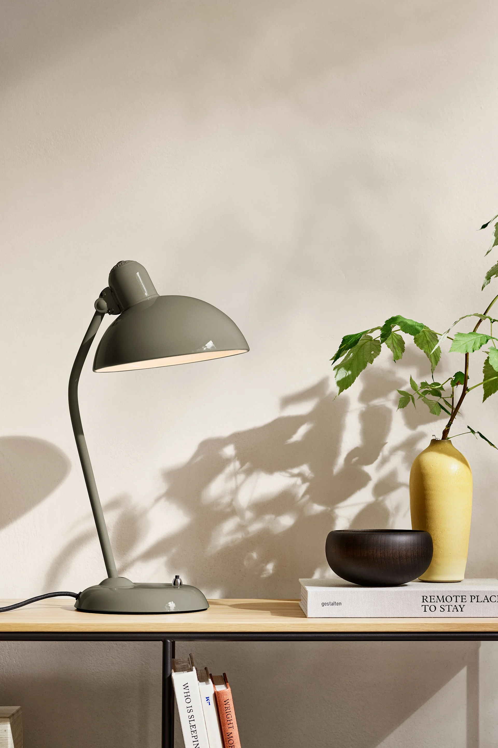 Bland inredningstrenderna för 2025 finns en naturlig nyans av olivgrönt, här ser du lampan från Fritz Hansen stående på ett sideboard. 