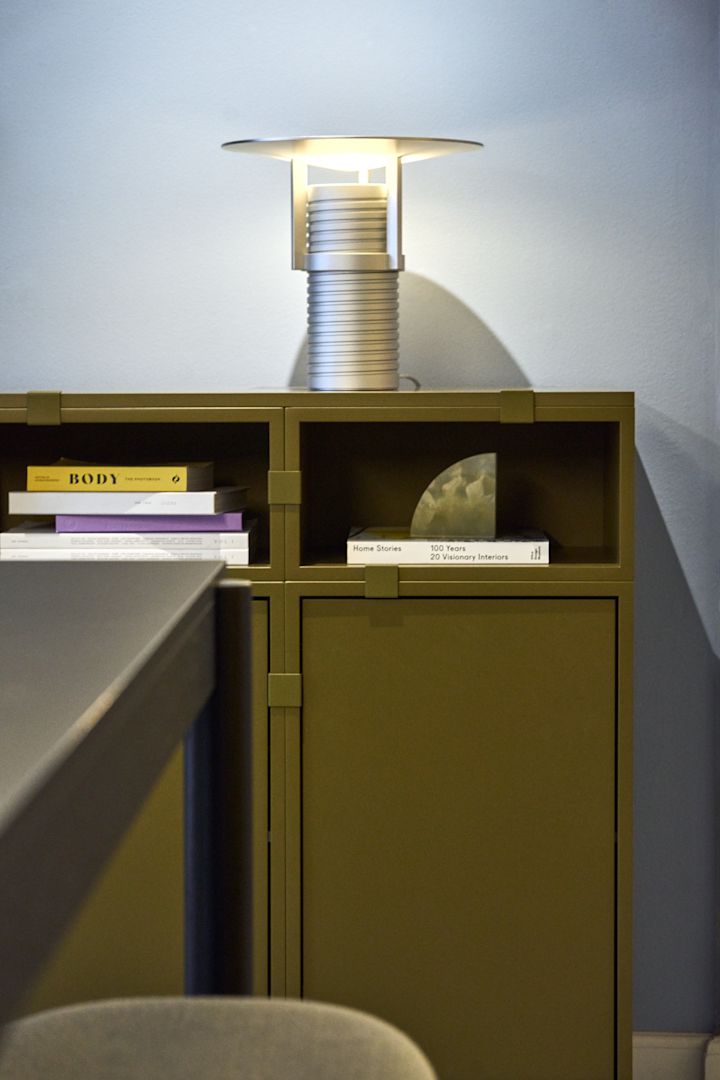 En grön hylla, byggd från Stacked-kollektionen, med den silverfärgade Set-bordslampan ovanpå, allt från Muuto.