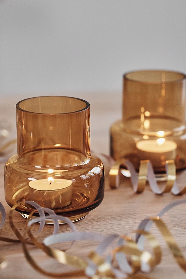 Ljuslyktor i glas i bärnsten sprider stämning på en nyårsdukning i guld. 