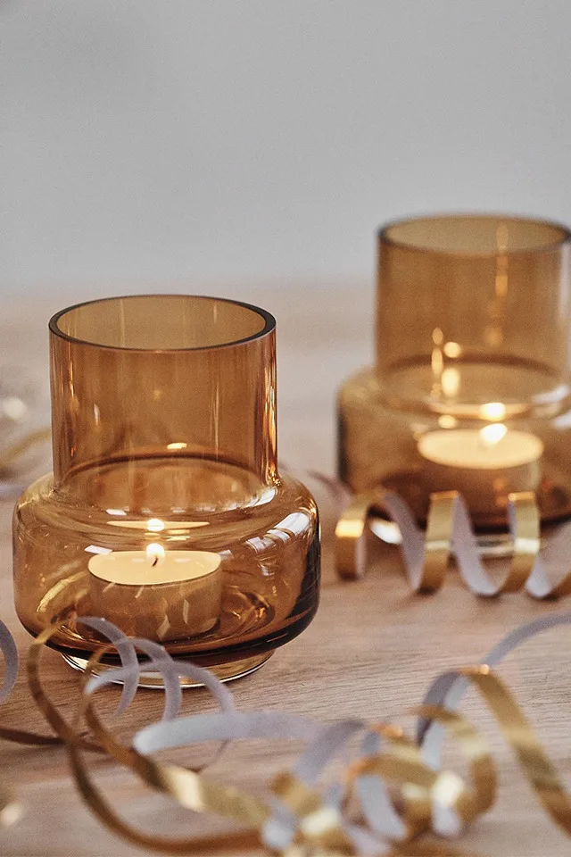 Ljuslyktor i glas i bärnsten sprider stämning på en nyårsdukning i guld.