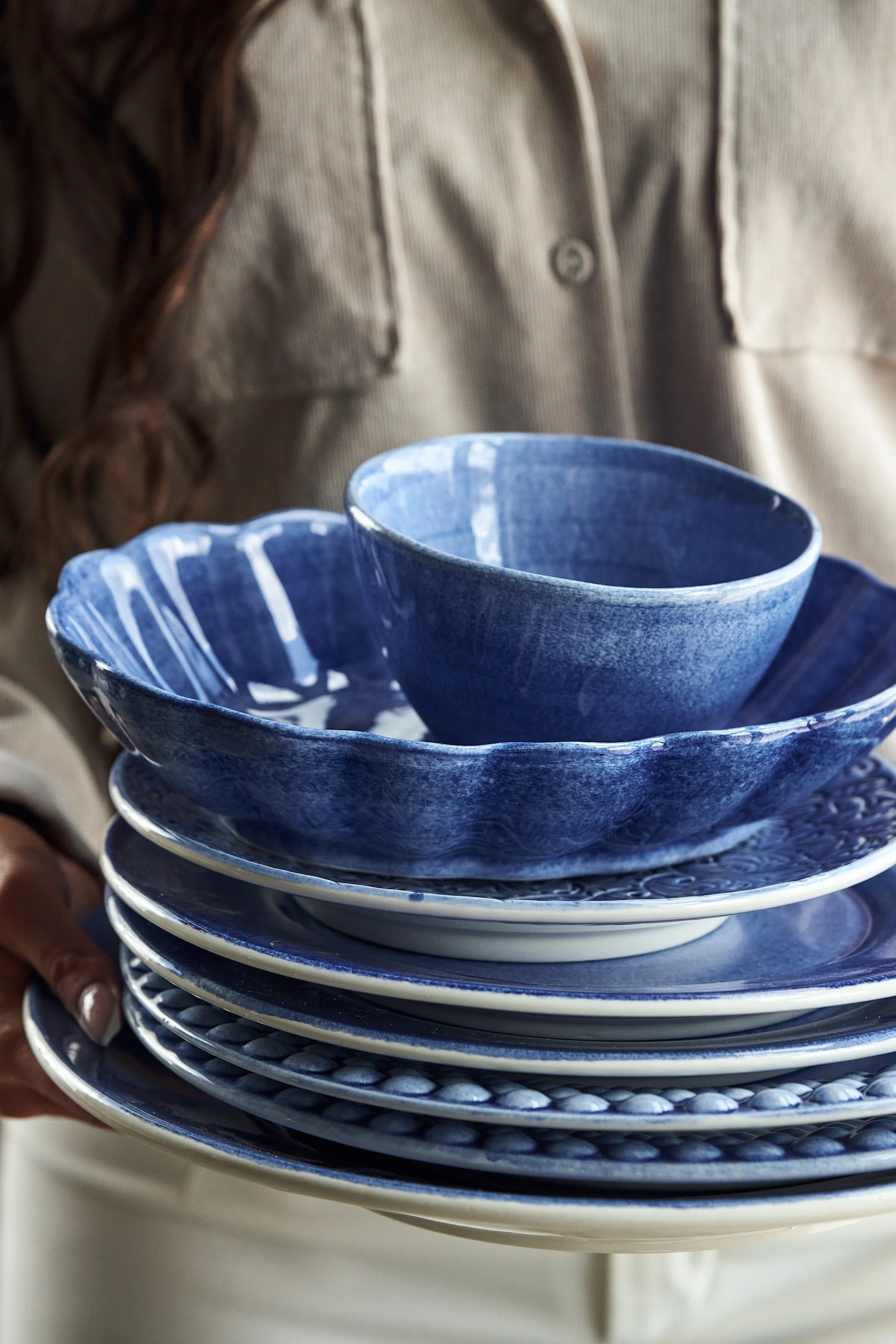 Ett dukat bord med Mateus porslin i blått och vitt i en grön miljö med utsikt över ett litet hus och en sjö.