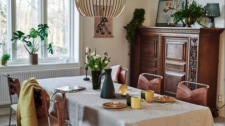 En matplats i retrostil med varma kulörer och naturmaterial med taklampa från Secto Design och Design House Stockholm stolar.