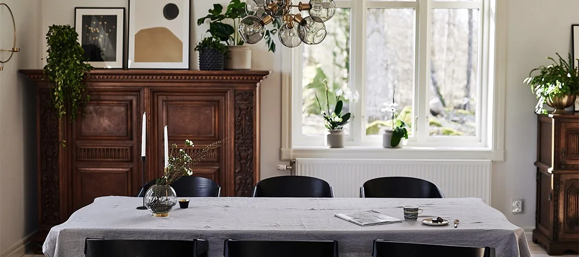 En stilren och dramatisk matplats i urban stil med matstolar i svart och taklampa i glas.