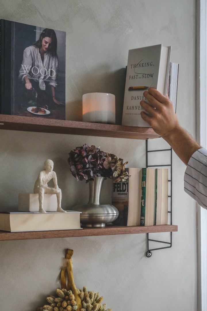 Inred ditt hemmakontor med en String-bokhylla med svarta gavlar och dekorera med skulpturer och böcker som Hannes Mauritzson. 