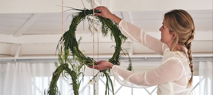 Drömska midsommarringar av blommor och grönt hänger över bordet