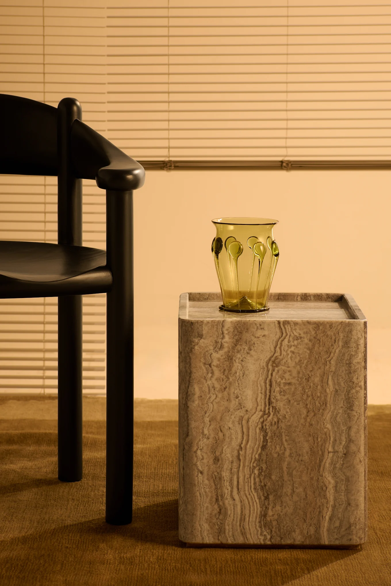 Sidobord i travertin från Gubi och stol från Gubi i svart furu, helt rätt för inredningstrender 2025. 
