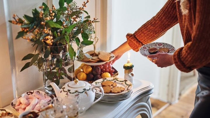 Glöggmingel med bord fullt med julgodis, frukt och pepparkakor tillsammans med rykande glögg. 