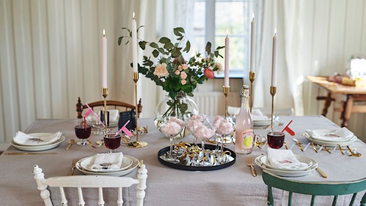 Duka till studentmottagning i pastellfärger med mässingsljusstakar från Skultuna, vitt porslin från Iittala och rund vas från ERNST. 