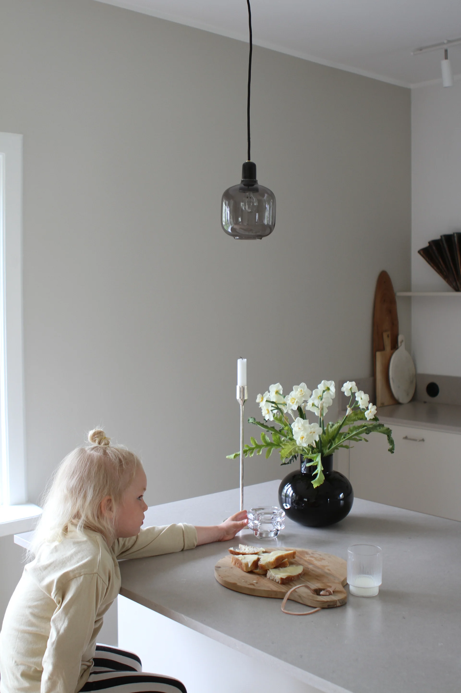 Moe of Swedens barn som sitter vid nyrenoverade köksön. Här ser du Amp lampa i grått och svart från Norrmann Copenhagen.