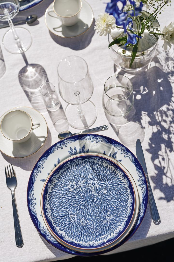 En klassisk midsommardukning med blåvitt porslin från Rörstrand, här Ostindia tallrik och Ostindia Floris assiett tillsammans med silverbestick på vit duk.