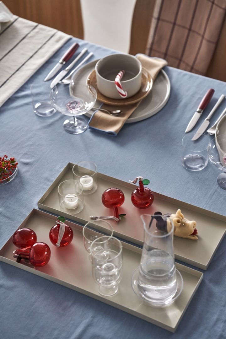 En elegant juldukning i 4 olika stilar enligt Nest Trends; Cultivate, Nurture, Boost och Share. Här är en dukning inom Share-trenden med beigea brickor från Cooee Design med Iittala glasäpplen i rött som dekoration.