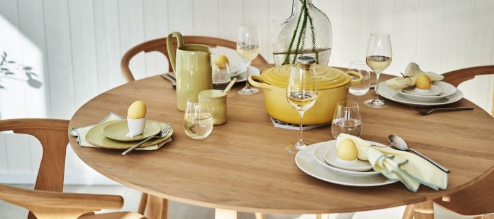 En stilfullt gul påskdukning med vitt porslin och gula accenter på bordet i form av ägg, servetter och gjutjärnsgryta.
