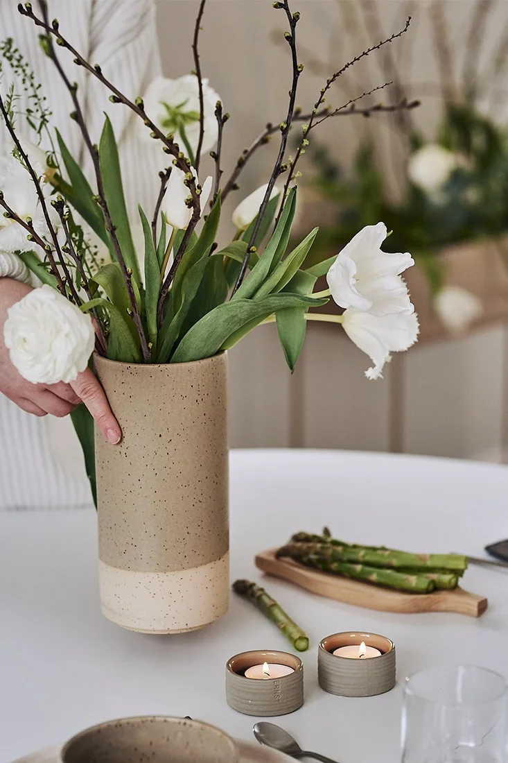 Spirande vårbukett i rustik vas från Paradisverkstaden och små ljuslyktor från ERNST pryder en vacker vårdukning. 