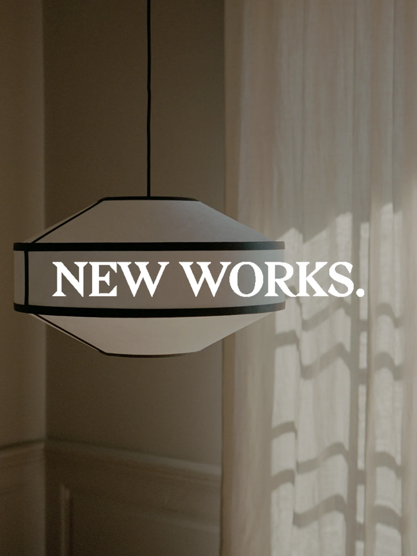 En bred, vit och mörkkantad taklampa hänger, med texten 'NEW WORKS.' överlagrad. Solljus kastar skuggor på en gardin.
