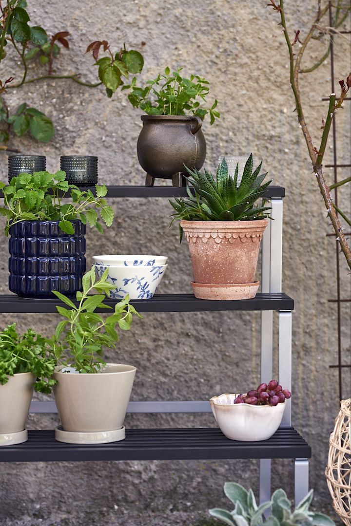 Krukor från Bergs Potter & ERNST på en blompiedestal på en uteplats i medelhavsstil. 