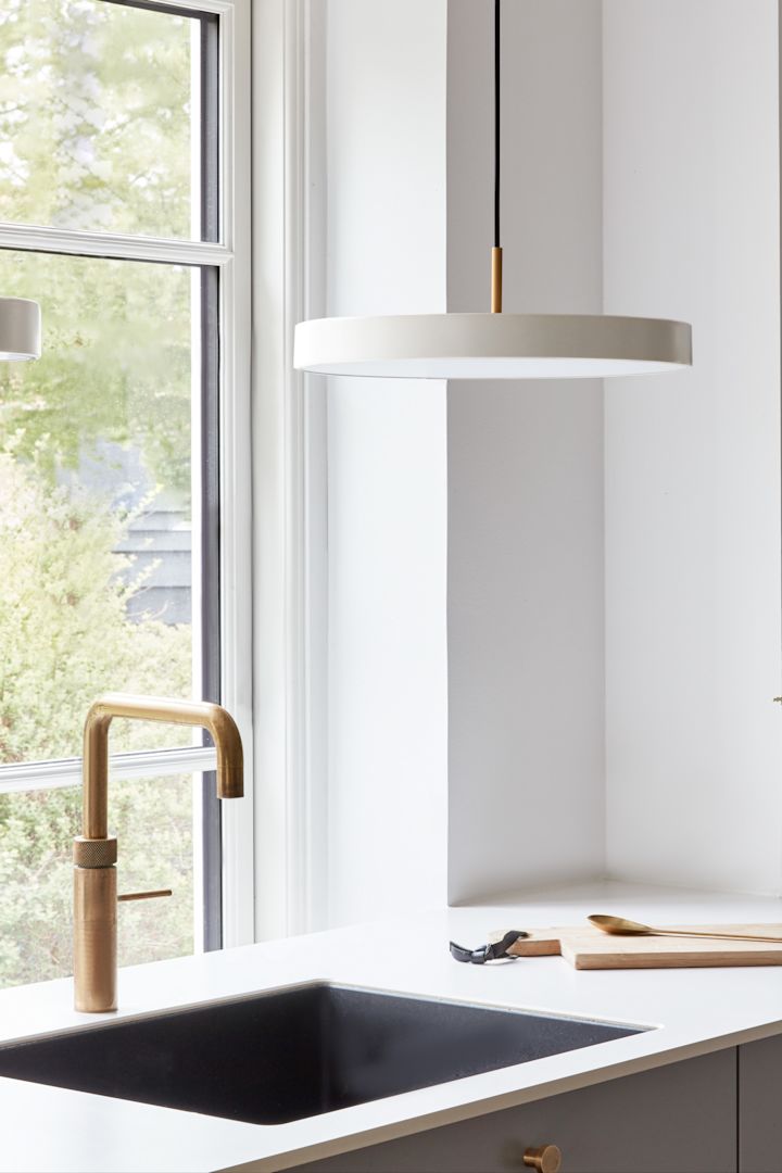 Använd stora pendellampor om du behöver lite mer ljus på platser som till exempel diskbänken. Här ser du pendellampan Asteria Micro i pärlvitt från Umage hängande ovanför ett handfat.