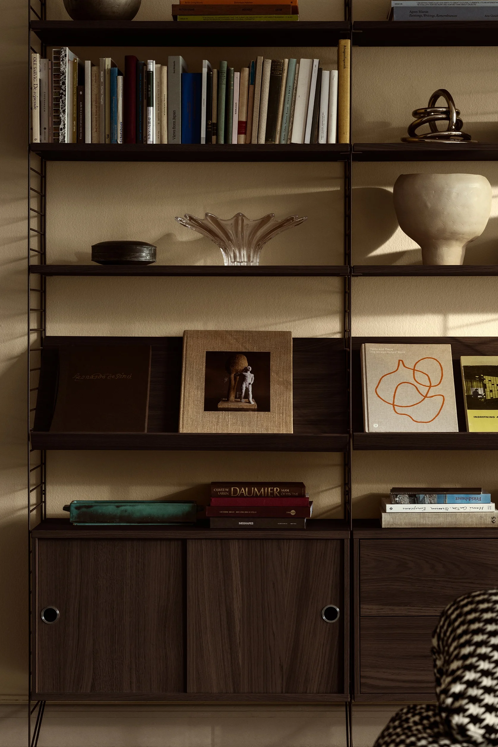 String hyllsystem passar perfekt för att dekorera vägg med. Här ser du hyllsystemet med personliga detaljer som böcker och skålar.