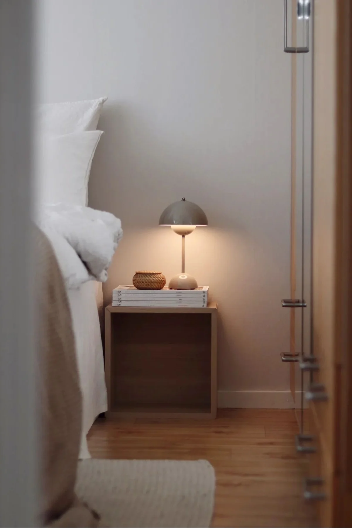 Flowerpot uppladdningsbar lampa från &tradition står brevid en säng och lyser.