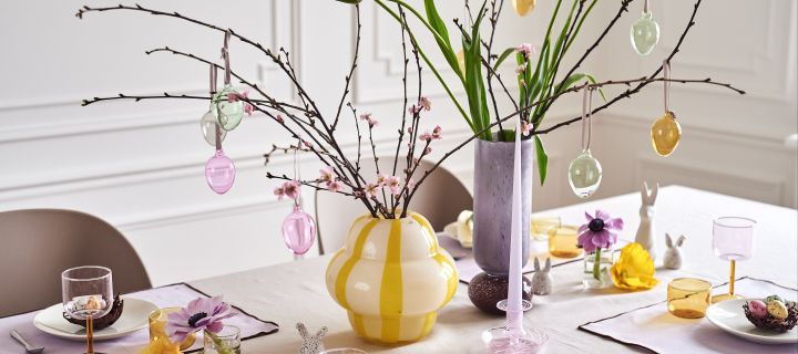 Skapa en festlig påskdukning i vårens pasteller med ett påskris i färgglada vaser såsom Curlie vas från By On och Dorit vas från Broste Copenhagen.