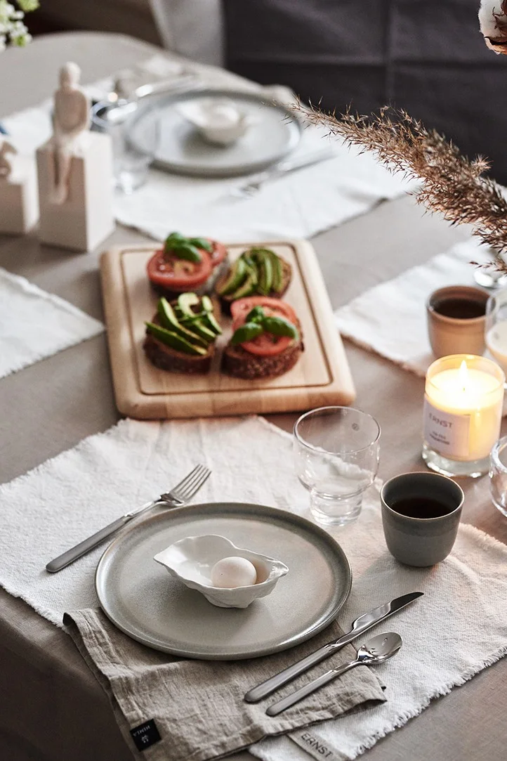 Duka till frukost med ett avskalat kuvert bestående av stengodstallrik och ERNST bordstablett i tyg.