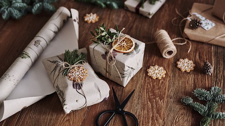 Julklapparna väntar på bordet, inslagna i blommig tapet för en mer hållbar presentinslagning till jul. 