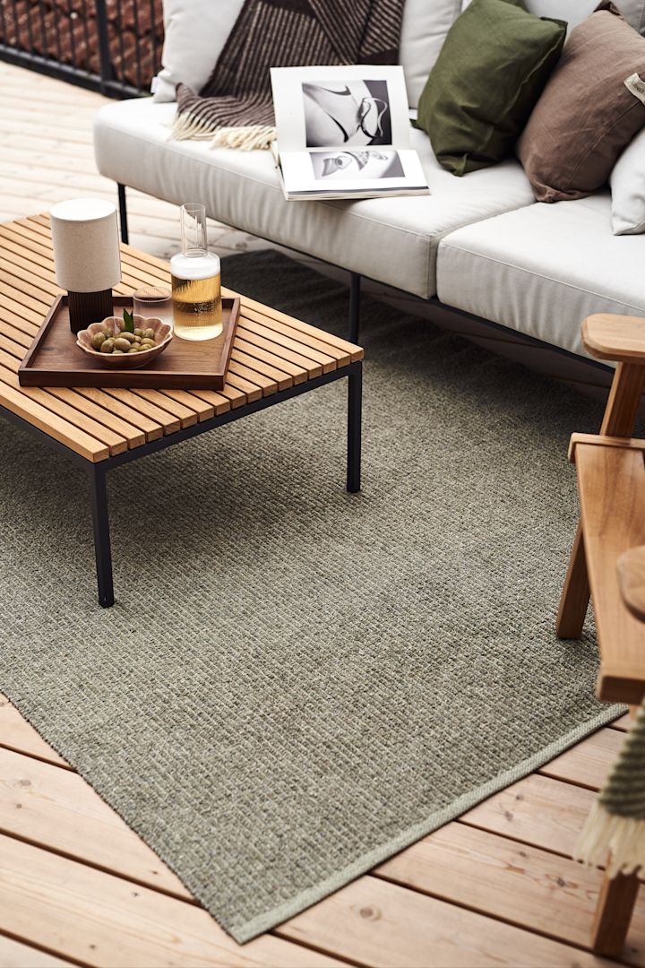 Här ser vi balkonginspo på hur du kan inreda med balkongmatta på din balkong. Här är den stora plastmattan Mellow i grönt från Scandi Living placerad under loungegrupp med ljusa dynor och lågt bord i teak.