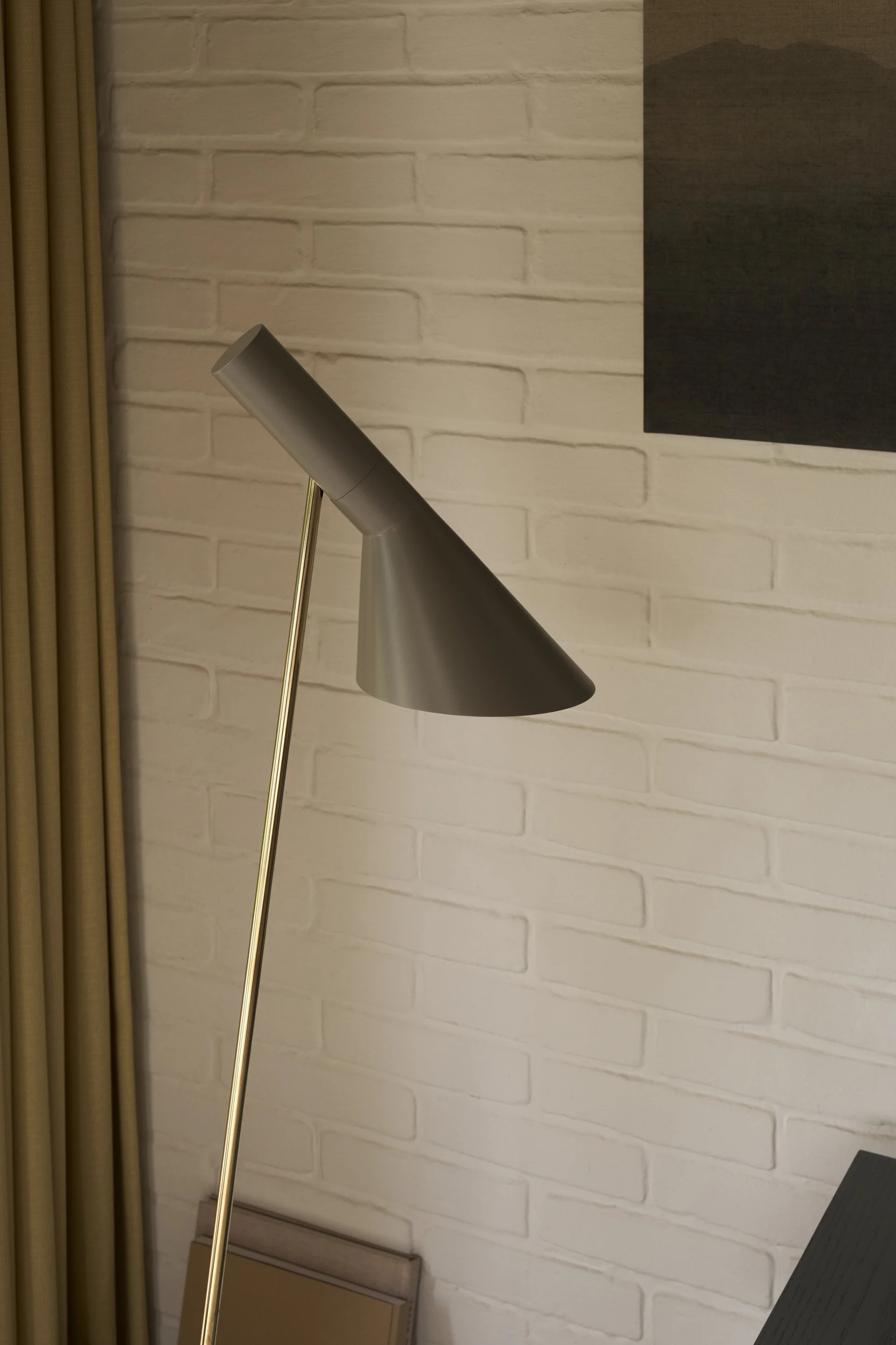 En AJ golvlampa i grått och mässing står i ett vardagsrum och visar på en klassisk designlampa. 