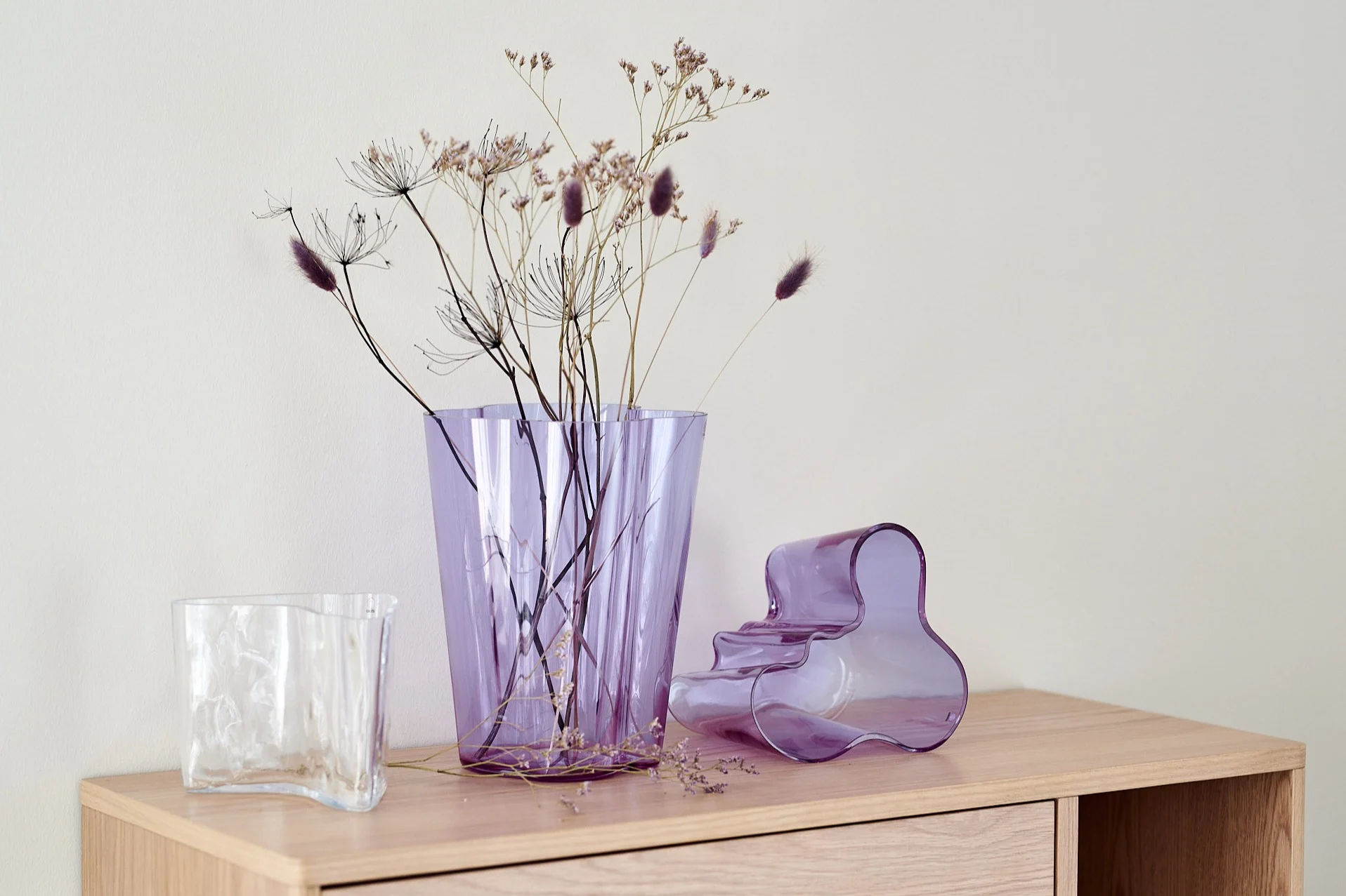 Jubileumskollektionen från Iittala med Alvar Aalto-vaser i ametistfärg med torkade blommor i.